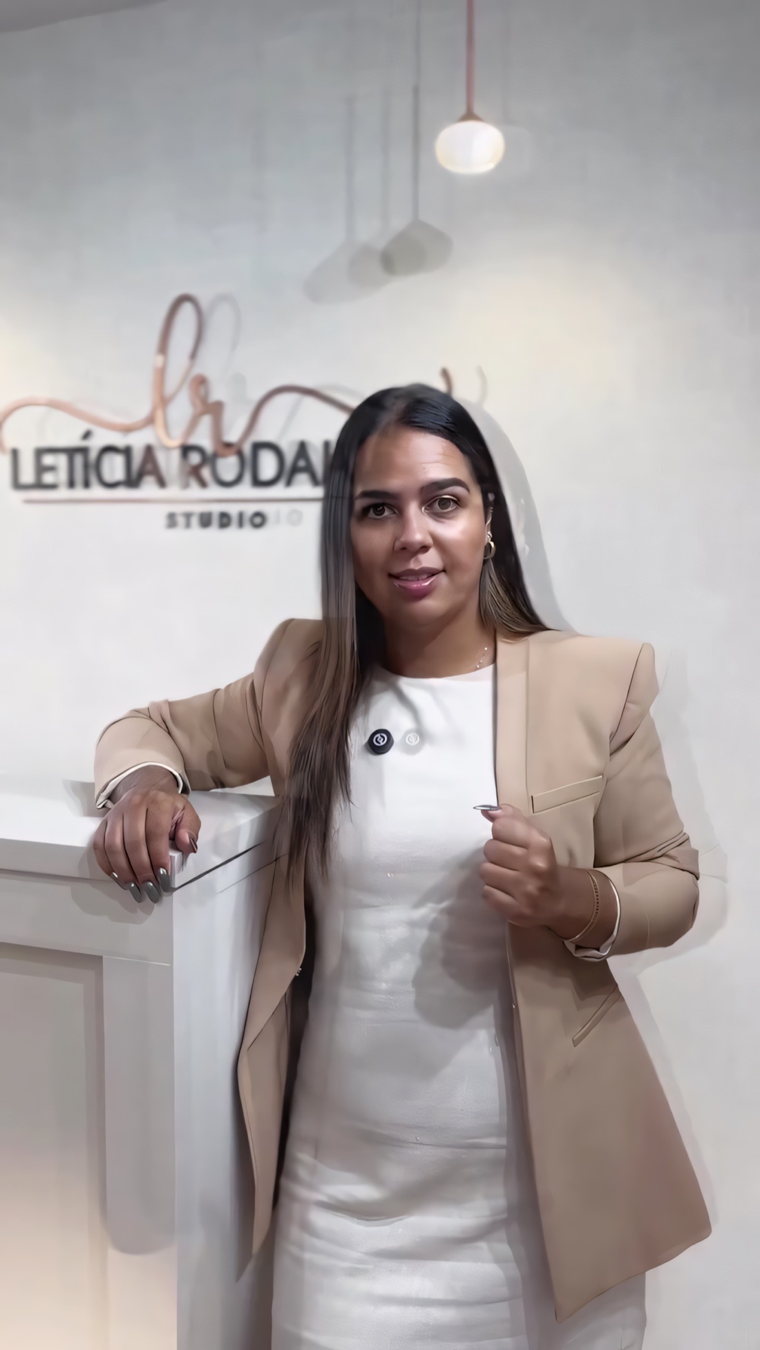 Letícia Rodaluge no estúdio, em frente ao logo na parede