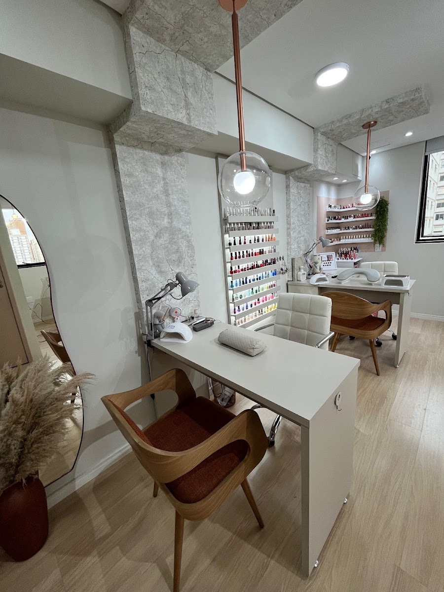Interior do estúdio: bancada clara, luminárias de cobre e parede de esmaltes iluminada